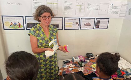 Associate Professor Nina Lansbury says the research team worked with students to create a 'period positive' environment for learning. A woman stands at the front of a classroom holding period products.